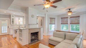 A spacious living room with a fireplace, a sofa, and a ceiling fan.