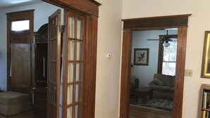A living room with a wooden door, a sofa, a coffee table, and a bookshelf. - 100-year old bungalow in the heart of the City, walking distance to Zilker Park! (Austin)