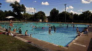 A public swimming pool with multiple lanes, surrounded by a fence, and shaded by trees. - 100-year old bungalow in the heart of the City, walking distance to Zilker Park! (Austin)