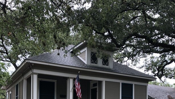 A single-story house with a front porch, a stone retaining wall, and a small garden. - 100-year old bungalow in the heart of the City, walking distance to Zilker Park! (Austin)