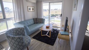 A modern living room with a sofa, a patterned armchair, a coffee table, and a TV. - "Gindanha" - country getaway (Borenore)