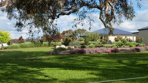 A well-maintained lawn with a large tree and flowering shrubs in front of a house. - "Gindanha" - country getaway (Borenore)