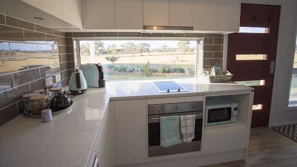 A modern kitchen with a large island, built-in oven, microwave, and a view of a garden through a large window. - "Gindanha" - country getaway (Borenore)