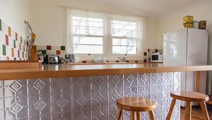 A kitchen with a wooden countertop, two stools, a refrigerator, a microwave, and a window with curtains. - Pizza oven; fire pit; lots of space indoor and outdoor, fires and aircon. Groups (Mudgee)