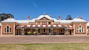 A historic building with a prominent year 1884 sign, a covered verandah, and a symmetrical facade with multiple chimneys. - Pizza oven; fire pit; lots of space indoor and outdoor, fires and aircon. Groups (Mudgee)