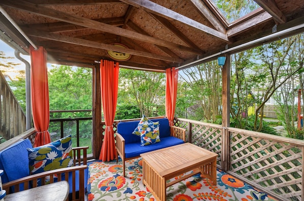 Un espace extérieur abrité, avec une table en bois et des sièges rembourrés bleus.