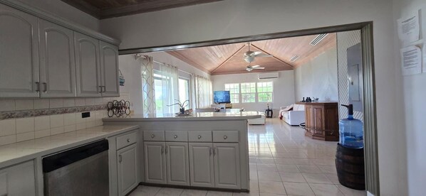 A kitchen with white cabinets, a central island, and a dining area with a sofa and table.