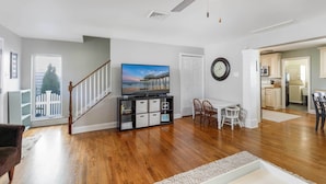 A spacious living room with hardwood floors, a ceiling fan, a flat-screen TV, and a staircase leading to another level. - Breezy Ocean City Home: Walk to Beach + Boardwalk! (Ocean City)