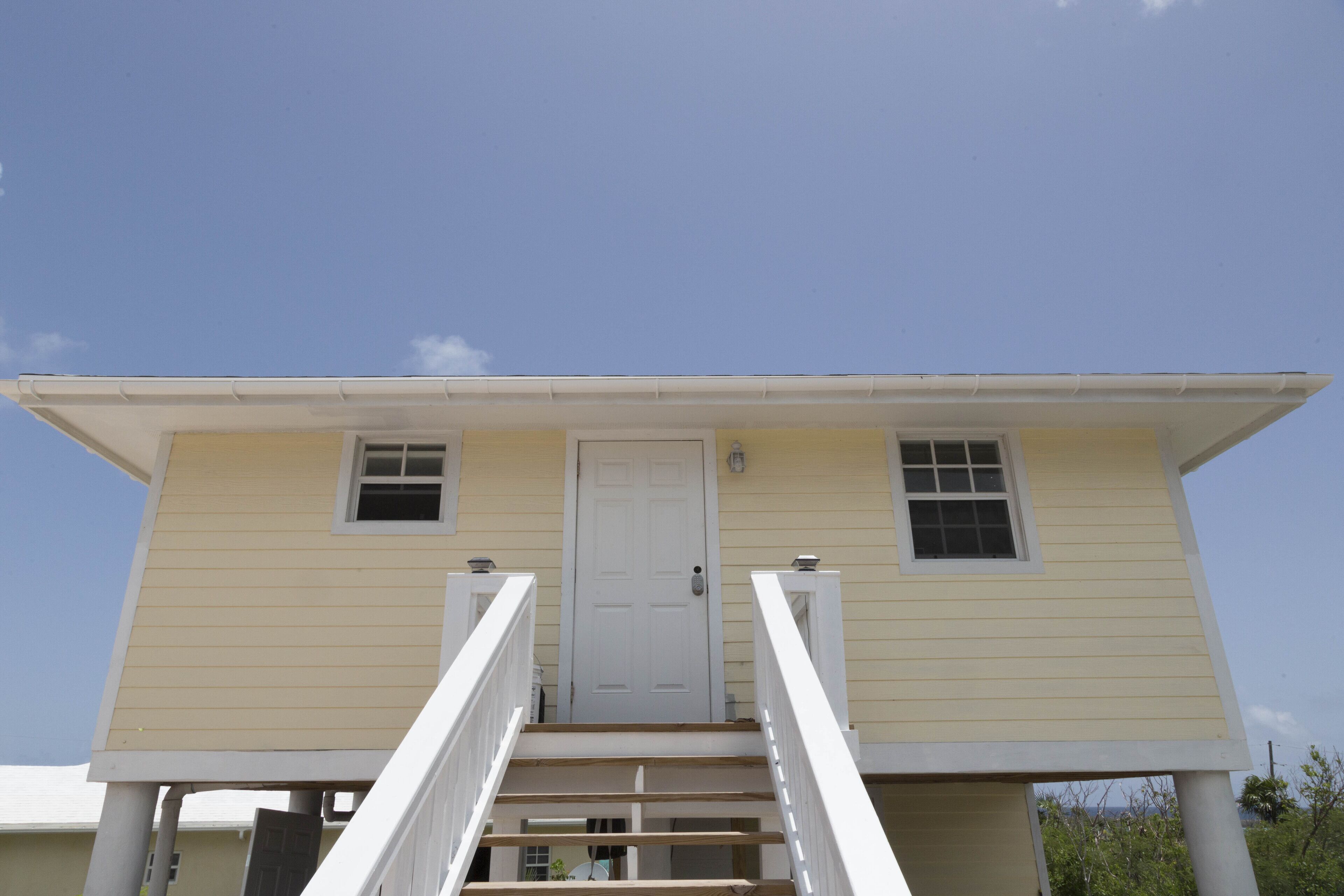 A two-story house with a front door, two windows, and a staircase leading to the entrance.