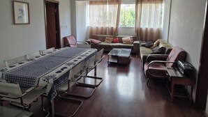 Une pièce comprenant une table à manger, des chaises, un canapé et une fenêtre avec des rideaux.