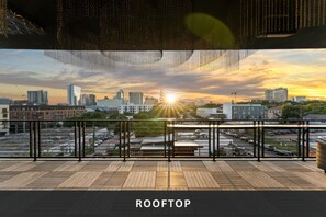 Eine Dachterrasse mit Blick auf die Skyline der Stadt im Abendlicht.