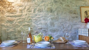 A dining table set with plates, glasses, a bottle of wine, and a vase with flowers. - Pet-friendly cosy cottage+poolclose to Florence. Great views. Capannina. sleeps2 (Londa (Florence))