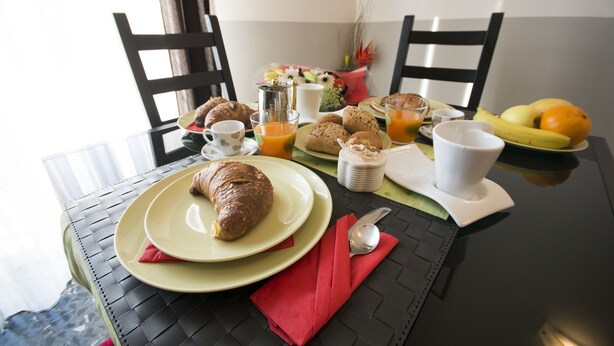 Une table de petit-déjeuner avec des croissants, du jus d’orange et des fruits.