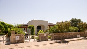 Un bâtiment moderne doté d’une façade en pierre, d’une entrée en arc de cercle et d’une allée menant à une porte grillagée.