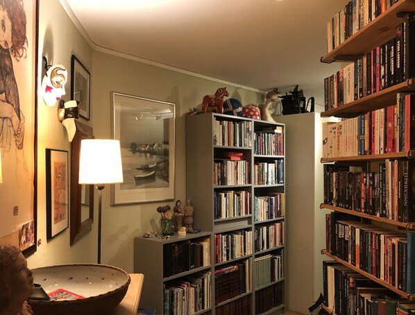 A cozy reading nook with bookshelves, a lamp, and a framed picture on the wall.