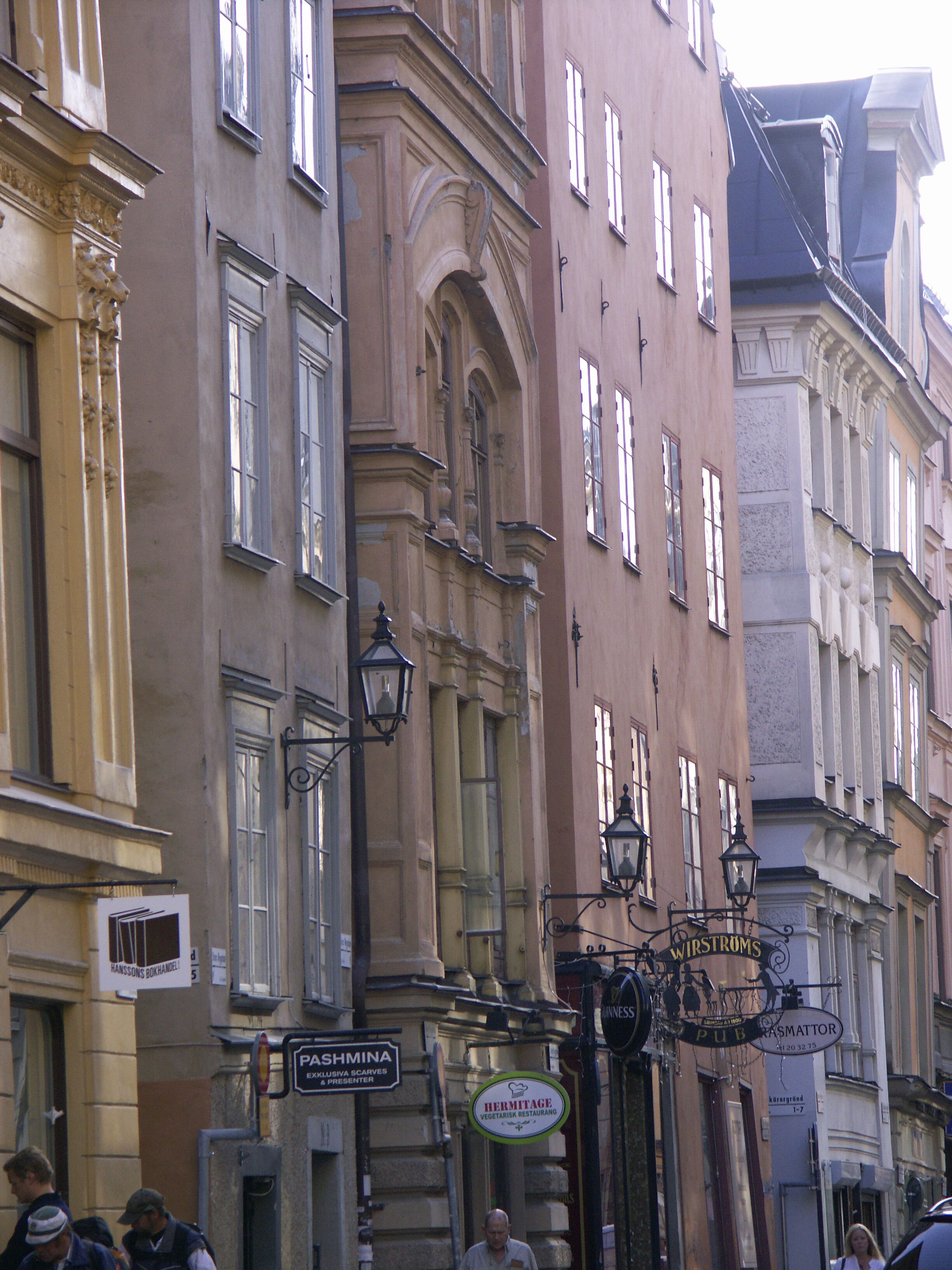 A street view with buildings featuring classical architecture, including ornate window frames and decorative street lamps.