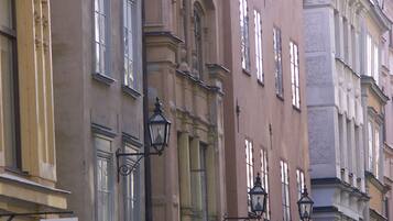 A street view with buildings featuring classical architecture, including ornate window frames and decorative street lamps.