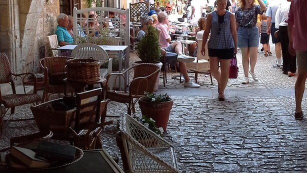 Ein Straßencafé mit Steingewölben, Tischen und Stühlen.