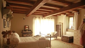 Ein Schlafzimmer mit Bett, Nachttisch, Lampe und Vorhängen.