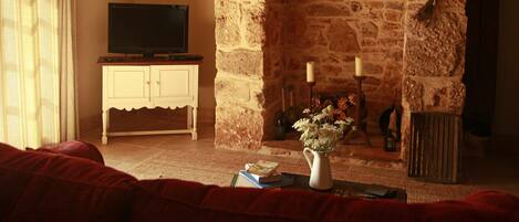 Una sala de estar acogedora con chimenea de piedra, un televisor sobre un mueble y un sofá rojo.