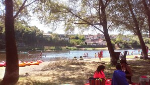 Eine Uferlandschaft mit Kanus, einem Picknickplatz und Häusern im Hintergrund.