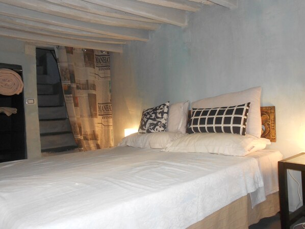A bedroom with a bed, pillows, a nightstand, and a wall with a poster. - apartment in the historic center of Genoa (Genova)