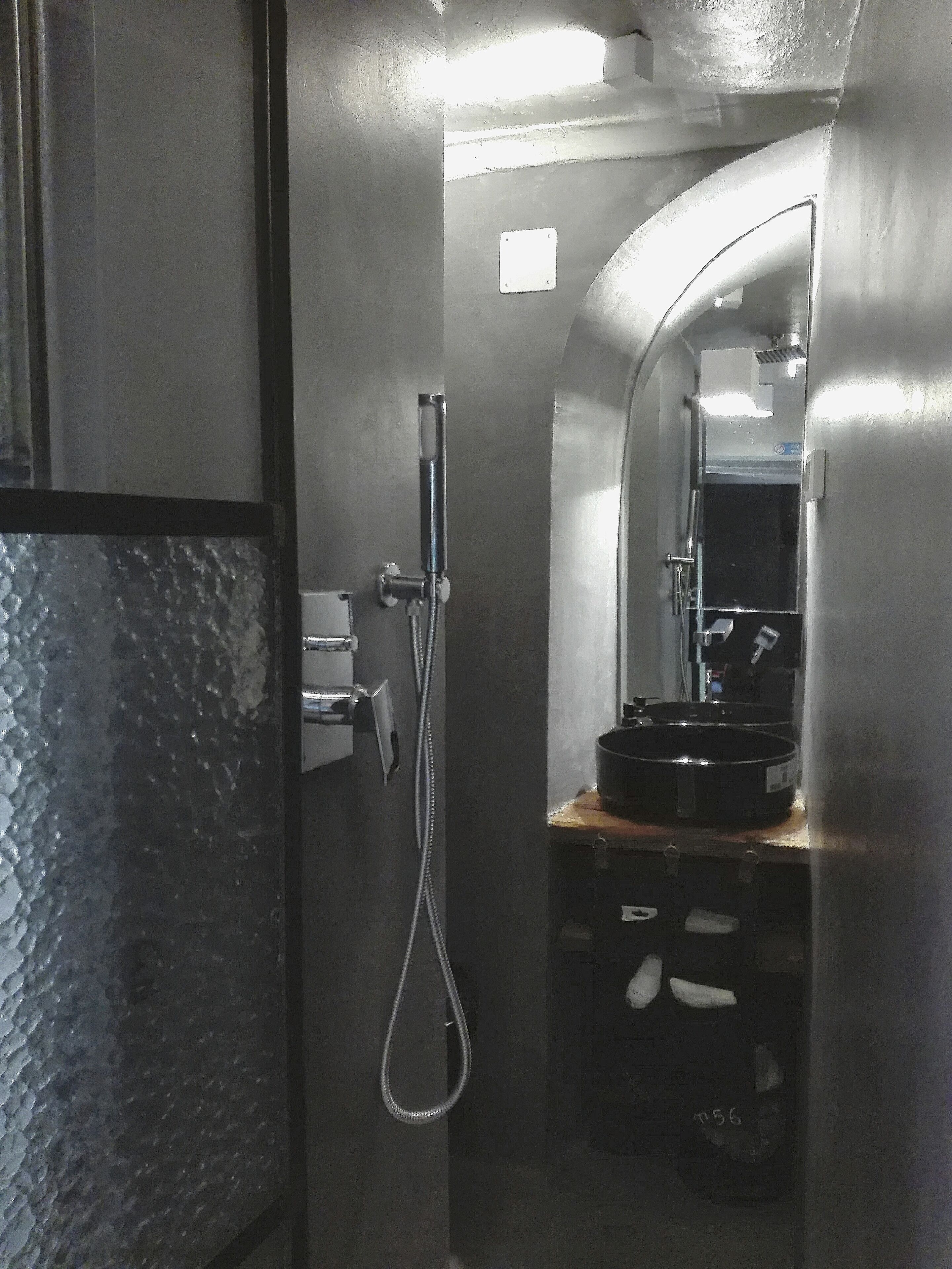 Une petite salle de bain comprenant une douche, un lavabo et un miroir.
