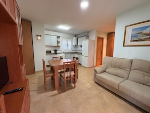 Um espaço compacto com área de refeições, cozinha compacta e sofá.