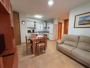 Um espaço compacto com área de refeições, cozinha compacta e sofá.