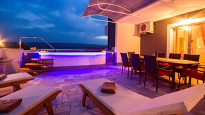 Terraza al aire libre con bar, sillones de descanso y zona de comedor.