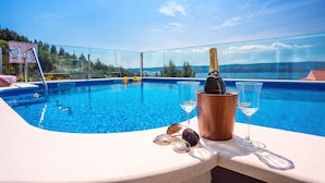 Zona junto a la piscina con vista despejada, una botella de champán y una copa.