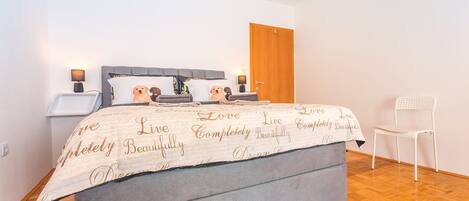 A bedroom with a bed, bedside tables, a chair, and a wooden door.