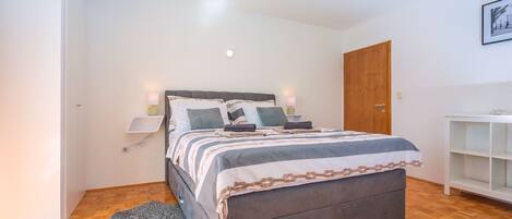 A bedroom with a bed, bedside tables, a ceiling fan, and a wooden wardrobe.