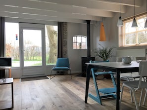 Enjoy a spacious room with a large window offering a view of the outdoors, a dining table, and a kitchen area with a stove and kettle.