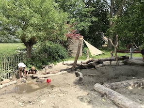 Explore the serene outdoor play area surrounded by trees and a wooden structure.