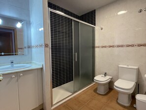 Bathroom features a glass-enclosed shower, single sink, and two toilets.