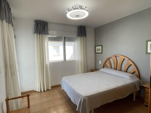 Cozy retreat with a single bed, bedside table, and window with curtains.