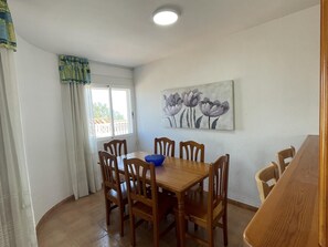 Enjoy meals in this dining area with a table and six chairs, a blue bowl, and a beautiful painting of flowers.