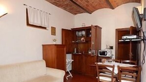A compact living space with a sofa, a dining table with chairs, a microwave, and a cabinet. - 45sqm two room apartment with independent entrance, kitchen living room, double bedroom (San Martino)
