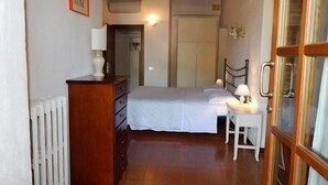 A bedroom with a bed, bedside table, lamp, dresser, and a radiator. - 45sqm two room apartment with independent entrance, kitchen living room, double bedroom (San Martino)