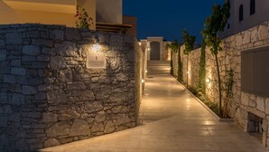 A stone-walled pathway leading to a building entrance at night, with illuminated signs and a clear view of the door. -  Villa Levanda,pool, walking distance from the beach and shops ,no car needed! (Πάνορμος Rethymno, Crete)