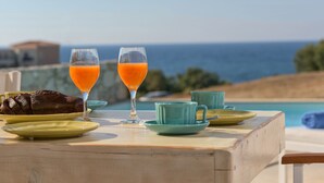 A table with a glass of orange juice, a plate with food, and a view of the sea. -  Villa Levanda,pool, walking distance from the beach and shops ,no car needed! (Πάνορμος Rethymno, Crete)