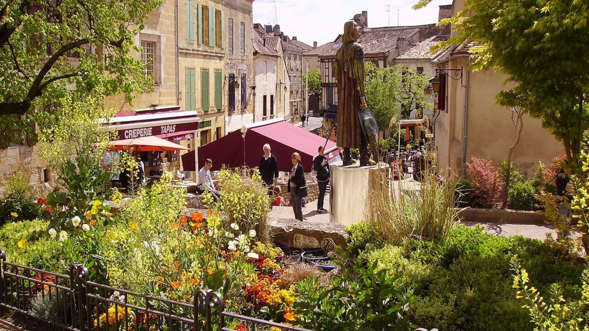Un cortile con un caffè, posti a sedere all'aperto e una statua.