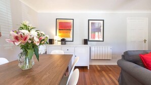 A modern living room with a wooden dining table, white cabinets, and a gray sofa. - Modern, Warm, Secure and Comfortable Oxford Apartment with easy access to City  (Oxford)