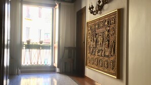 A hallway with a polished floor, a large ornate wall decoration, and a door leading to an outdoor area with a view of buildings. - VILLA FRARI IN CAMPIELLO (Venezia)