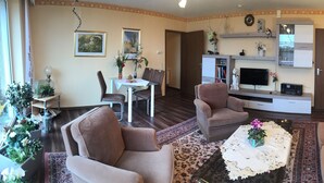 Un salon comprenant un ensemble de canapés, une table basse, un téléviseur et un coin repas avec des chaises et une table.
