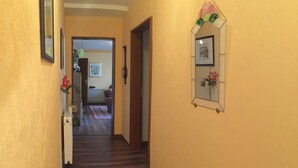 Un couloir doté d’un plancher en bois, de murs jaunes et d’une porte donnant sur une autre pièce.