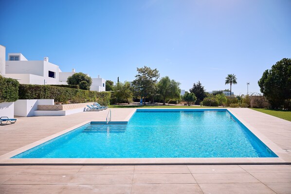 A rectangular swimming pool with a tiled deck surrounding it.