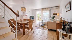 A spacious living area with a dining table, wicker chairs, a sofa, and a TV. - Nice holiday house with pool and sea view (Porches)
