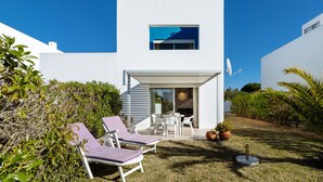 A modern white house with a patio area featuring two lounge chairs and a table. - Nice holiday house with pool and sea view (Porches)